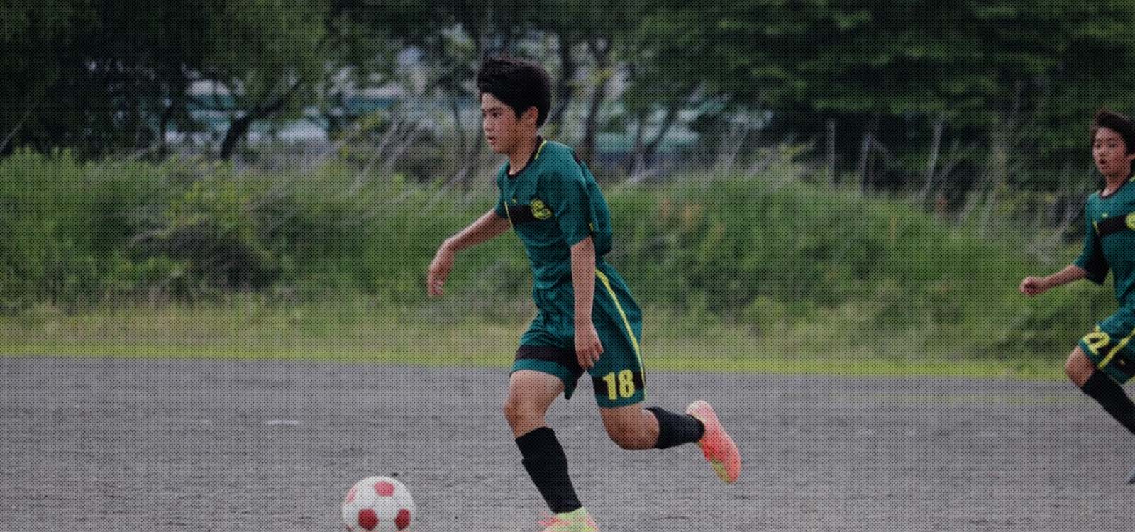 ジョガドール静岡の選手がサッカーボールをドリブルしている写真