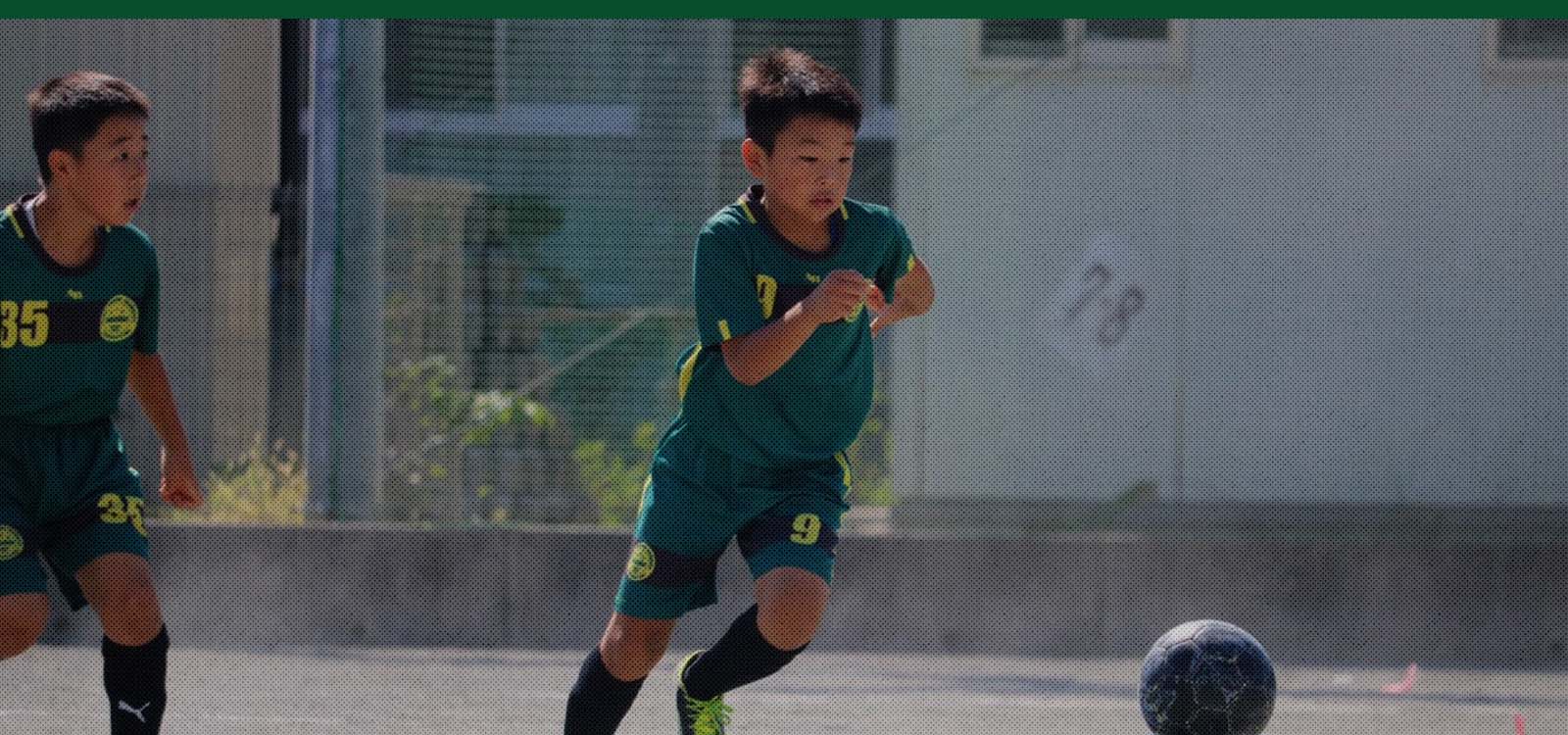 ジョガドール静岡の選手が黒いサッカーボールを蹴って走っている写真