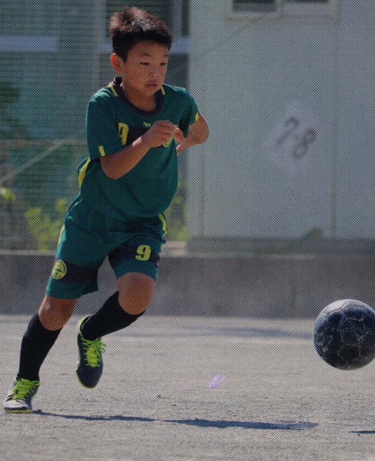 ジョガドール静岡の選手が黒いサッカーボールを蹴って走っている写真